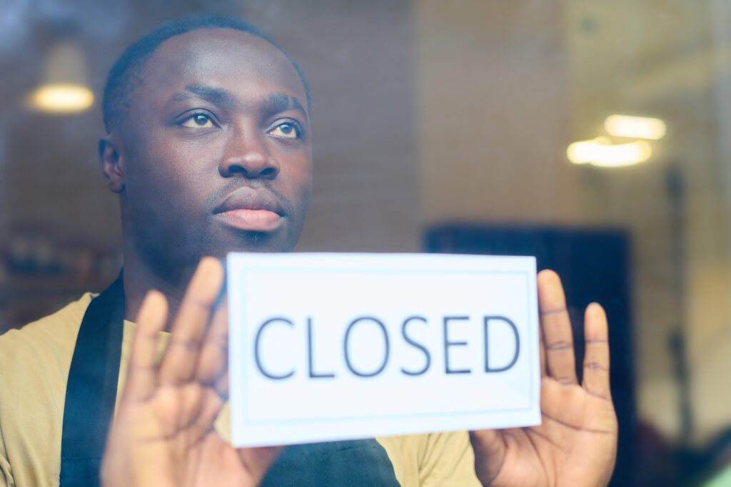 Homem preto empunha uma placa onde está escrito closed, uma alusão ao feriado do dia do trabalhador