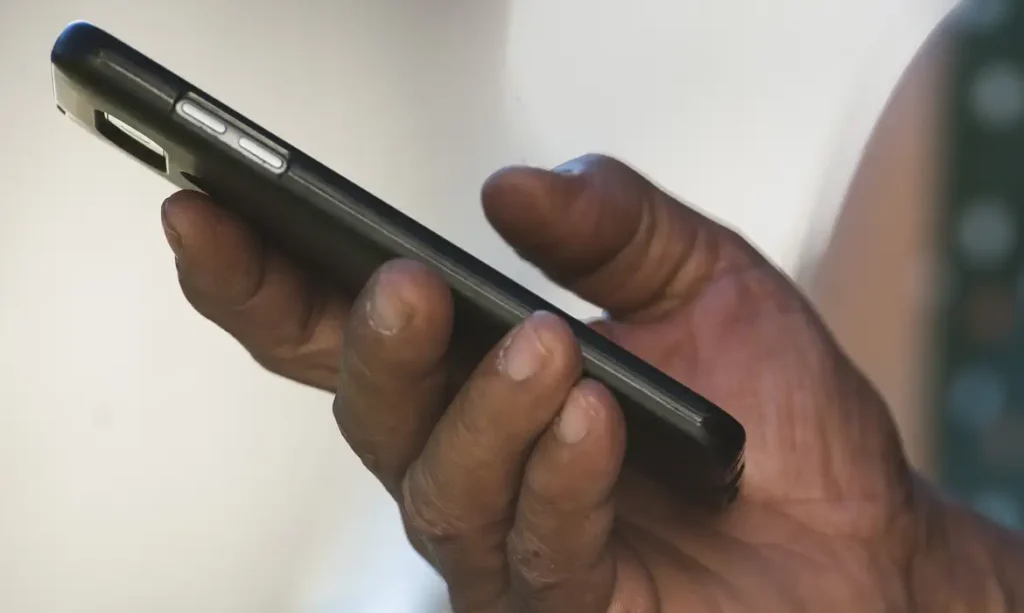 A imagem mostra um homem segurando um celular.