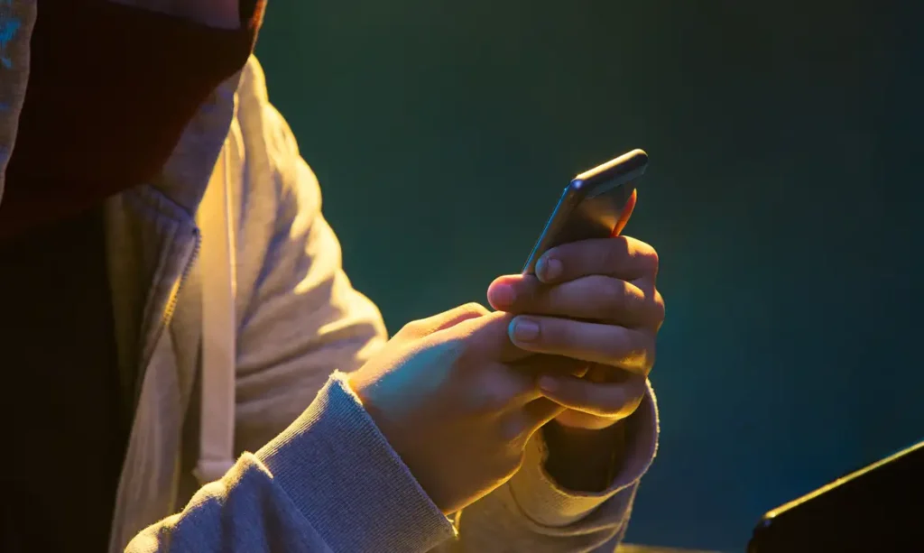 A foto mostra uma pessoa com um celular na mão.