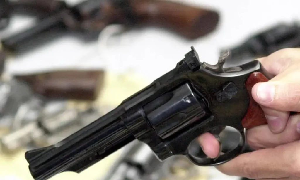 A foto mostra uma pessoa segurando uma arma de fogo preta.