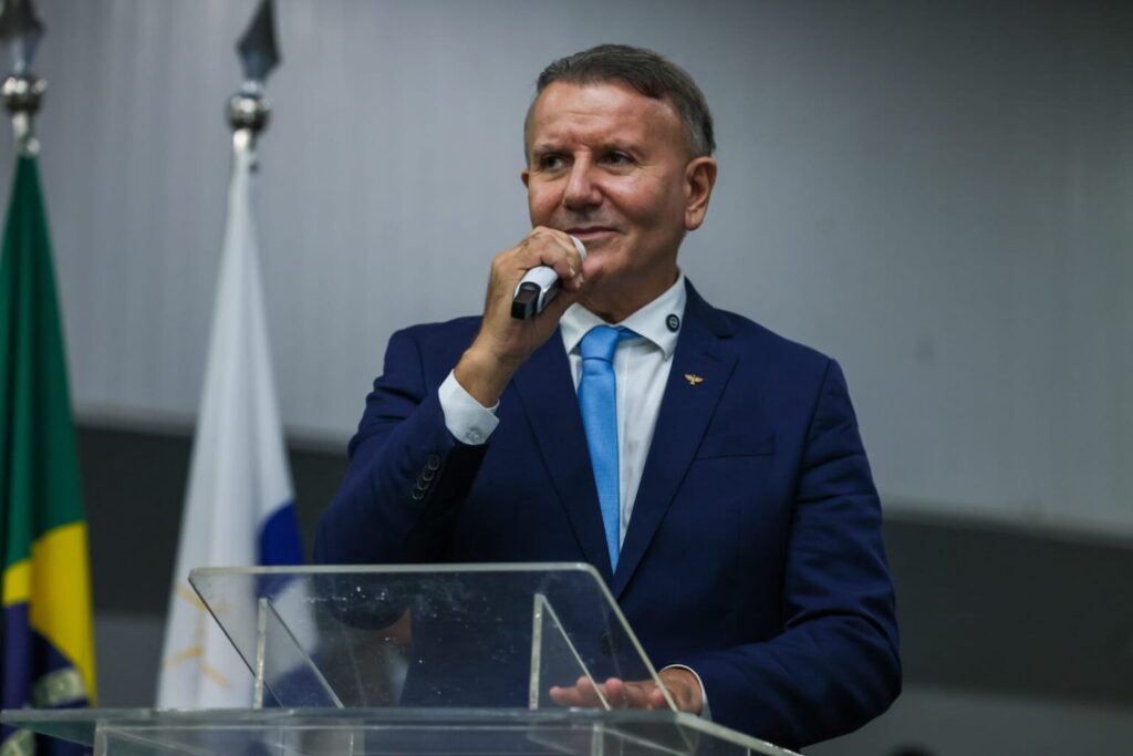 A foto mostra o prefeito de Palmas durante um pronunciamento. Ele é um homem branco com cabelos grisalhos.