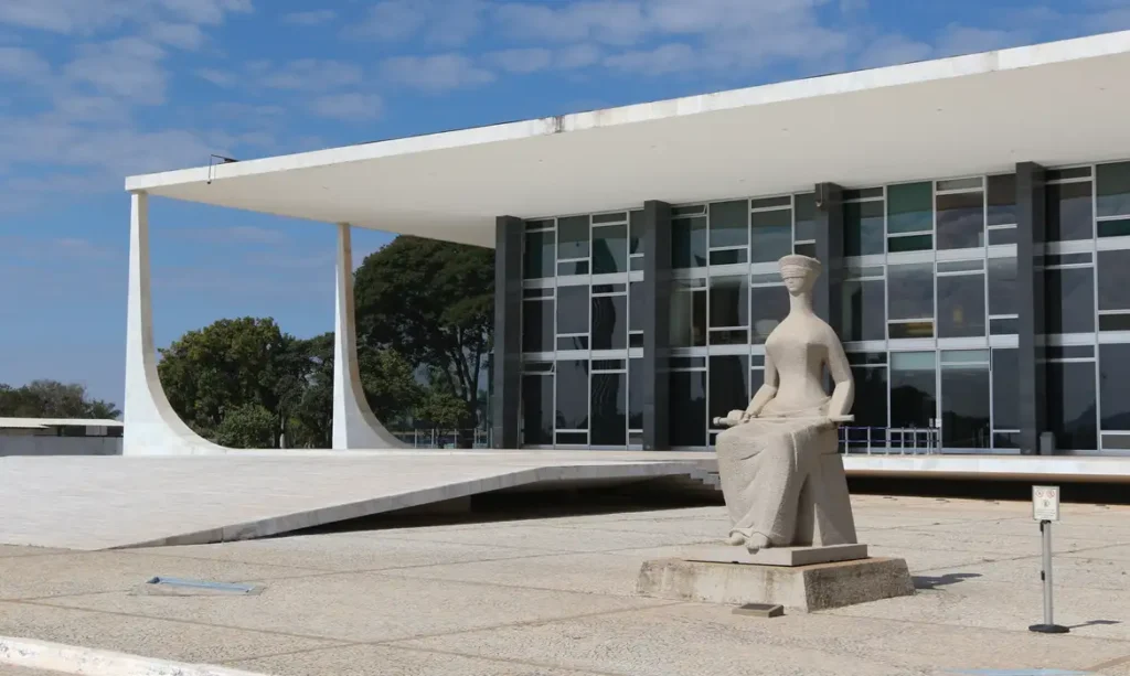 A foto mostra a fachada do STF em Brasília, com a estátua da Justiça em frente ao prédio.