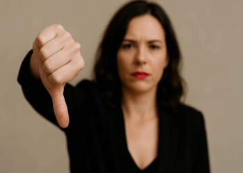 Mulher faz sinal negativo apontando o dedo polegar para baixo com a mão fechada