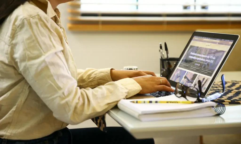 A foto mostra uma mulher trabalhando em um computador.