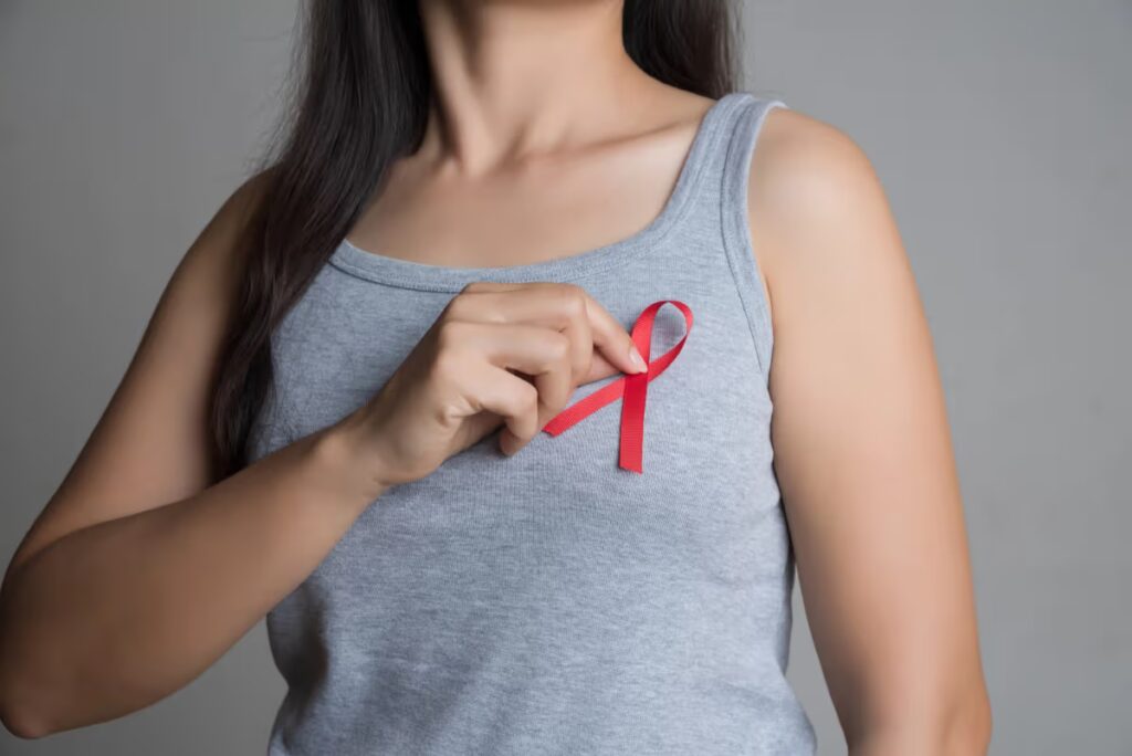 mulher coloca fita vermelha que simbiliza HIV na blusa