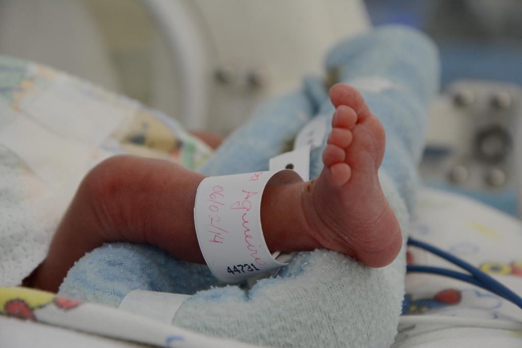 A foto mostra um bebê recém-nascido com a pulseira de identificação no pé.