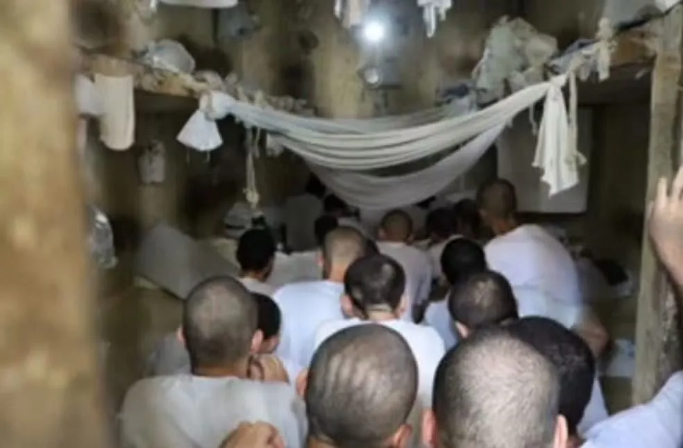 Detentos de costas dentro de presídio