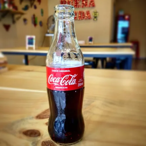 Garrafa de Coca-cola sendo servida numa mesa de bar