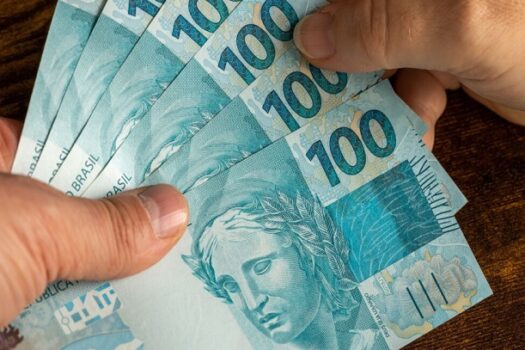 Cédulas de dinheiro sendo seguradas por uma mão