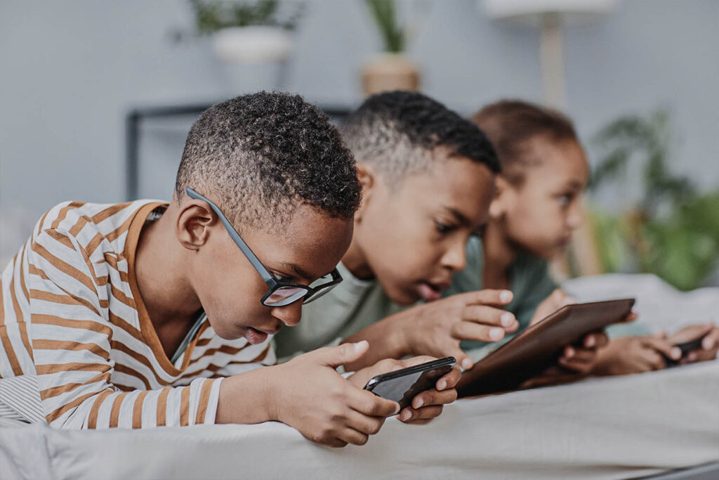 Crianças olhando celulares e tablets