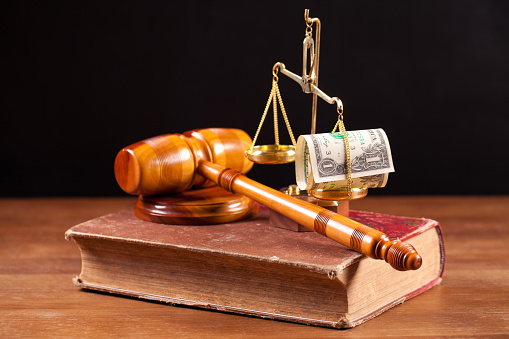 martelo de juiz sobre a constituição e dinheiro pendurado na balança da justiça