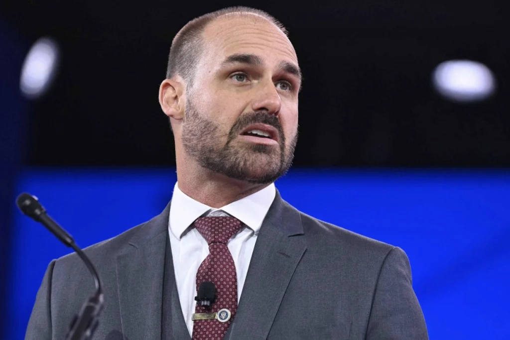 Eduardo Bolsonaro de terno e gravata falando num pulpito