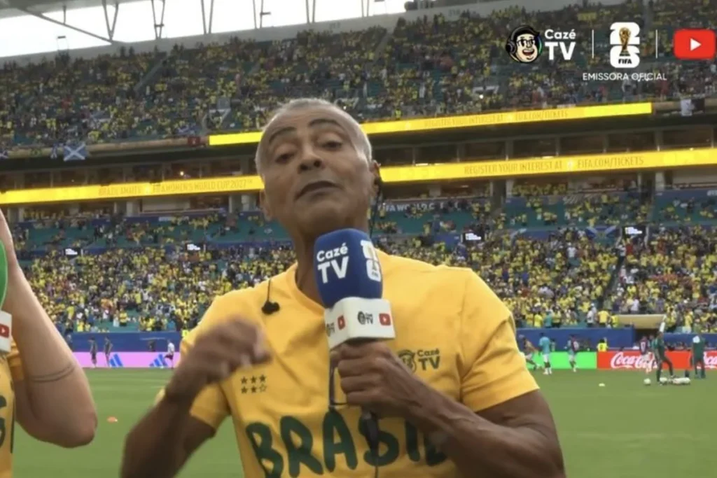 Romário com camiseta verde e amarela em campo na copa do mundo de 2026 falando no kcrofone da TVCazé