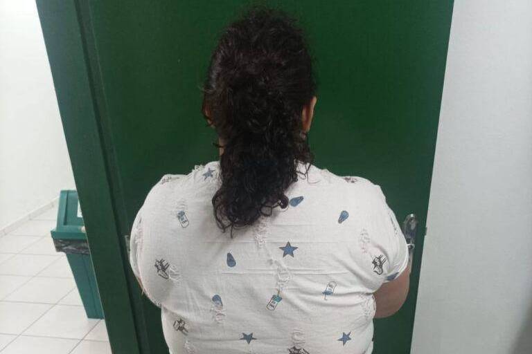 Mulher presa, de costas.