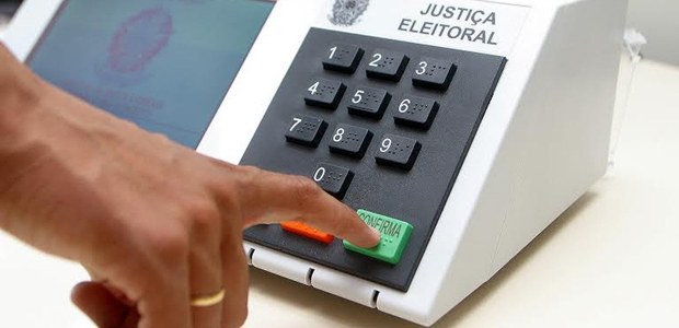 Mão de uma pessoa votando na urna eletrônica