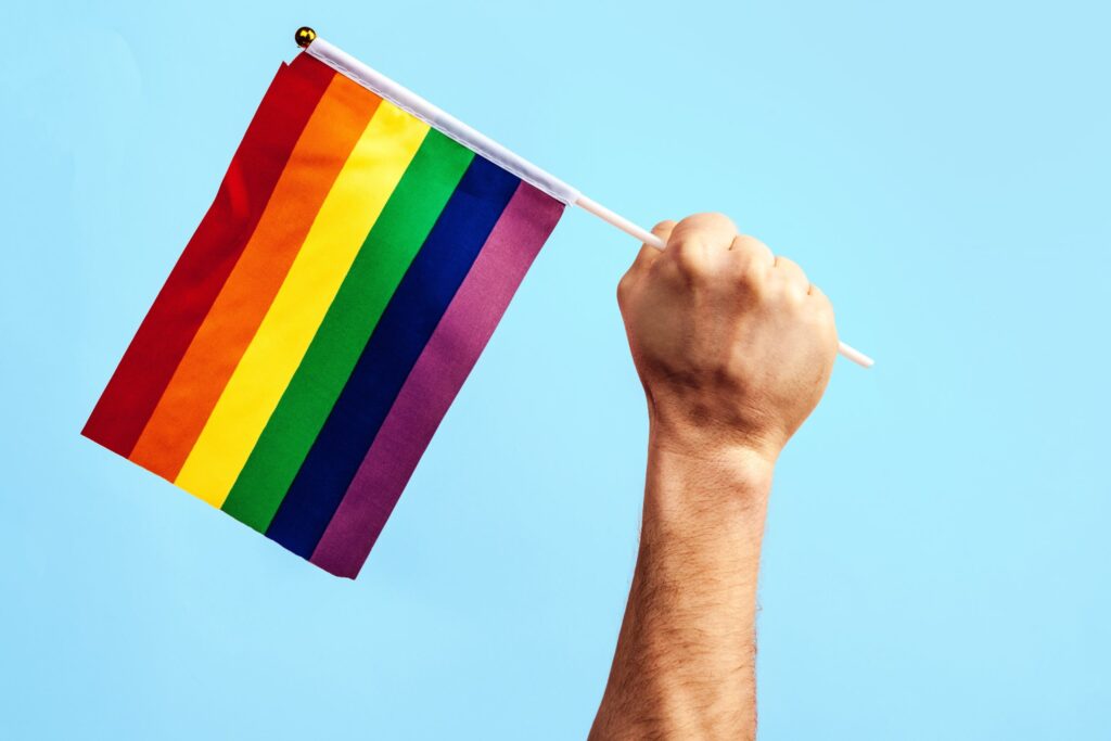 imagem de uma mão segurando uma bandeira gay