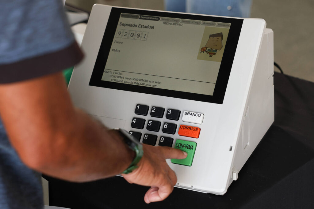 mãos digitando voto em uma urna eletrônica