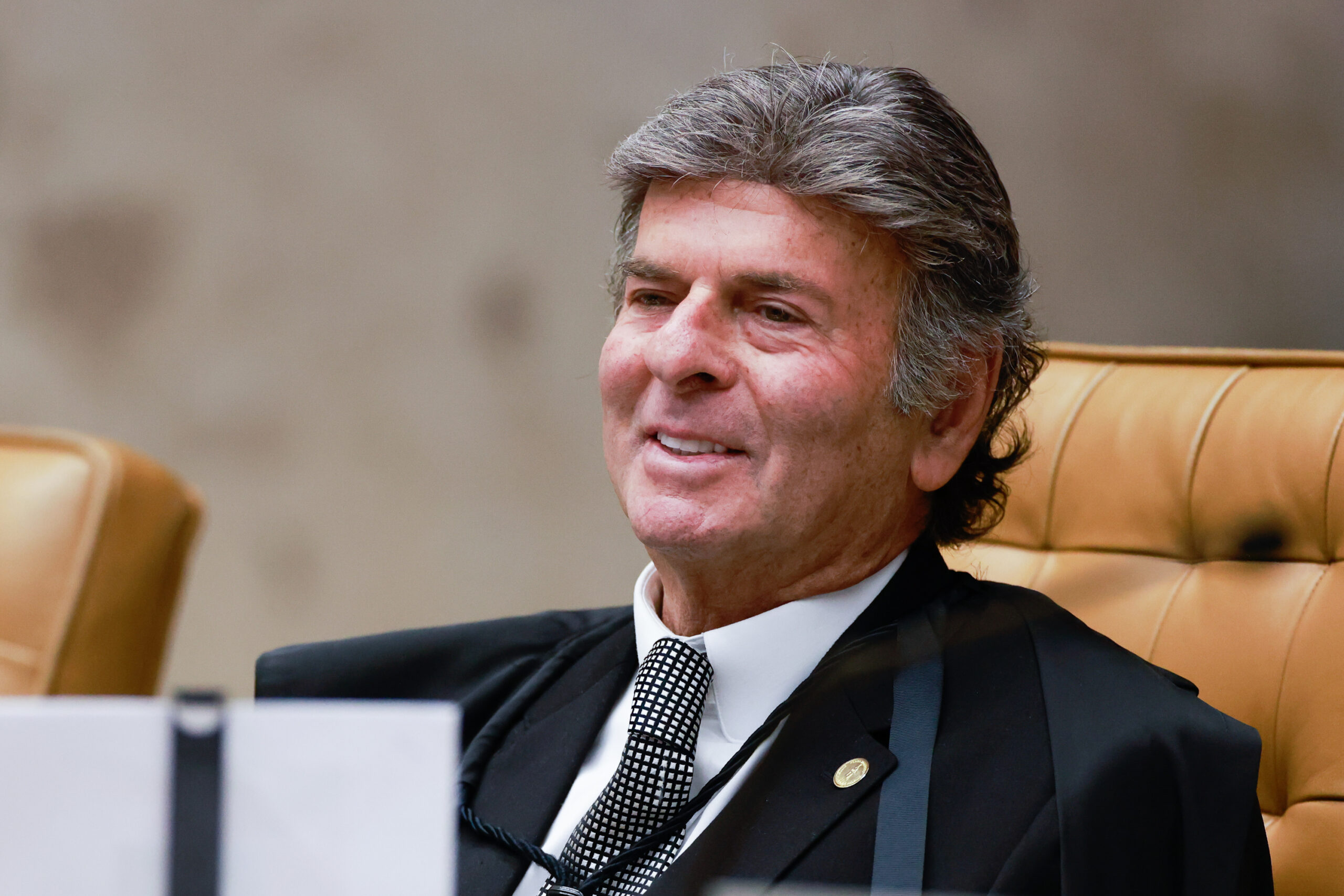 Ministro Fux no plenário do STF com semblante leve, risonho