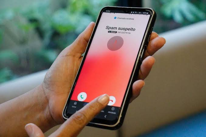 Mão de pessoa segurando celular que aponta ligação suspeita de spam